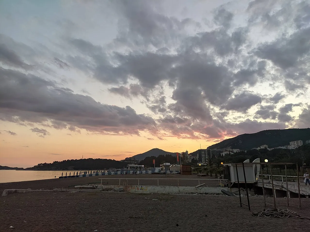 Bečići beach at sunset with a wooden pier reaching into the sea