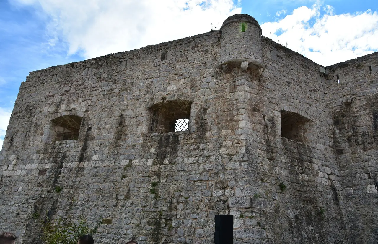 The massive stone walls and corner turret of the Budva citadel against a blue sky