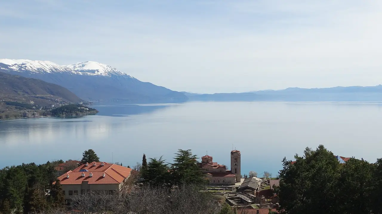 Lake Ohrid with a lakeside church and snow-topped mountains across the water, North Macedonia