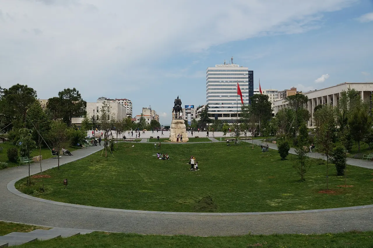 Skanderbeg Square in Tirana with the equestrian statue, a tall hotel and people on the lawns