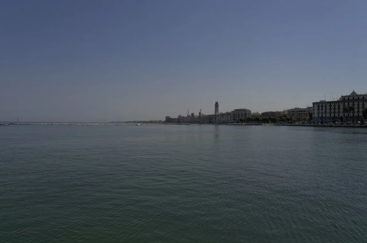 Quayside at the port of Bari with the breakwater and the harbour lighthouse under a clear sky