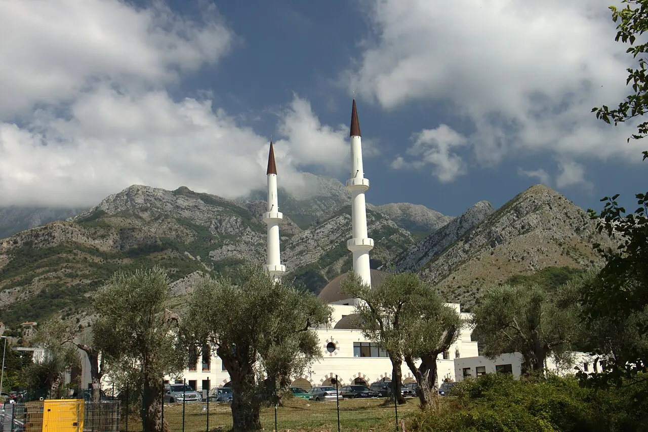 Two white minarets of a Bar mosque against the grey slopes of Mount Rumija