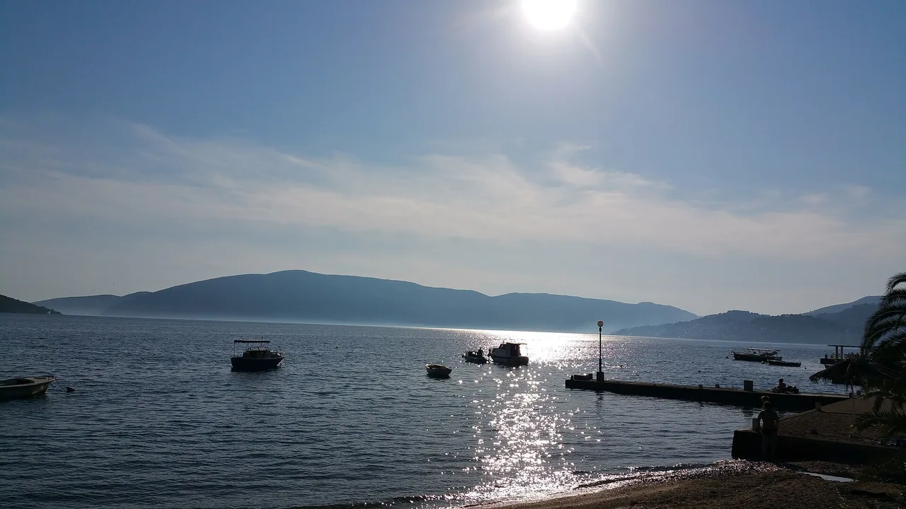 Small boats moored at Kumbor in the evening light with the Kumbor Strait and Luštica hills behind