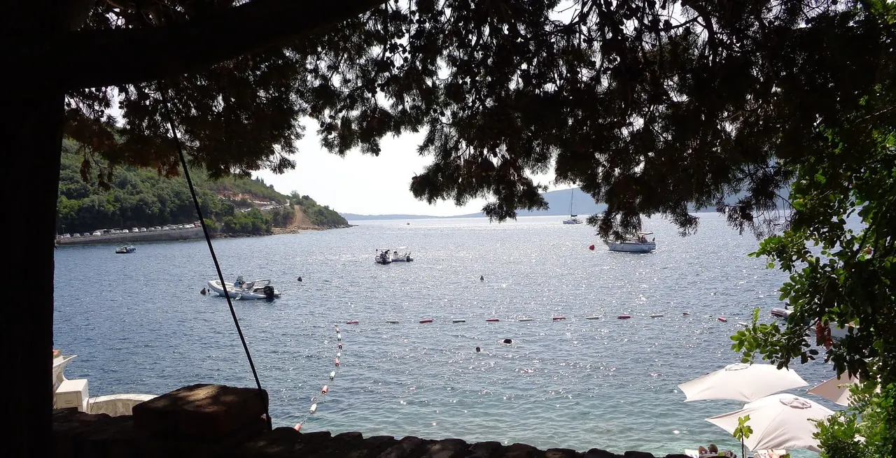 Buoyed swimming line off the shore at Rose on the Luštica peninsula, with small boats moored beyond it