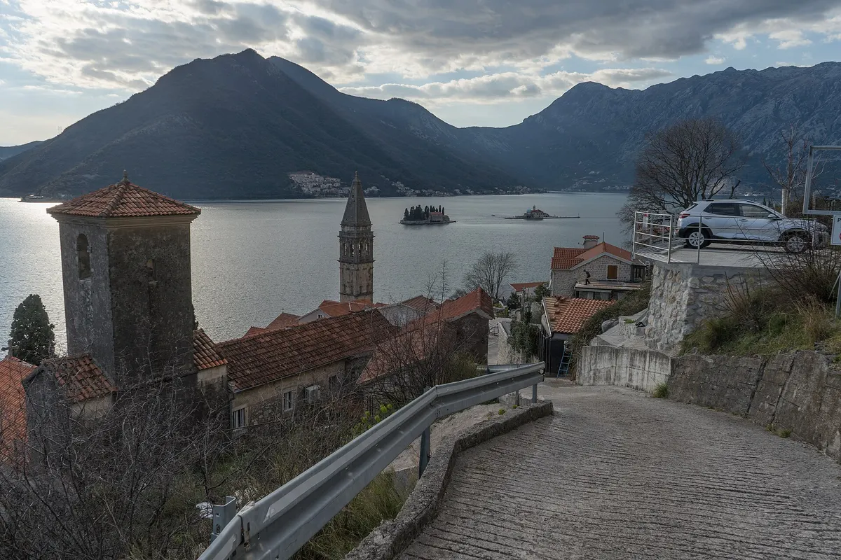 Perast's bell tower and rooftops with the two islands, Our Lady of the Rocks and St George, in the bay behind