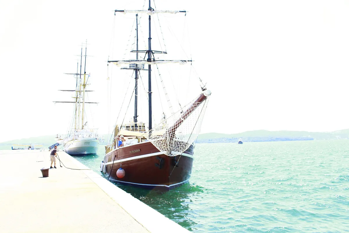Tall sailing ships moored along the quay at Porto Montenegro marina in Tivat, turquoise water alongside