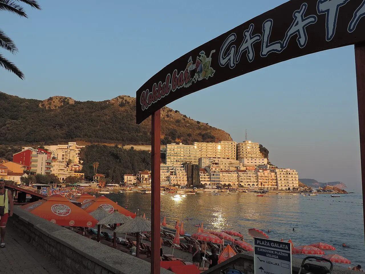 The long arc of Bečići beach with resort buildings and steep mountains behind