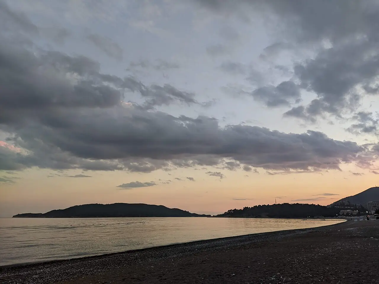 Wooden pier reaching into the Adriatic from Bečići beach at dusk