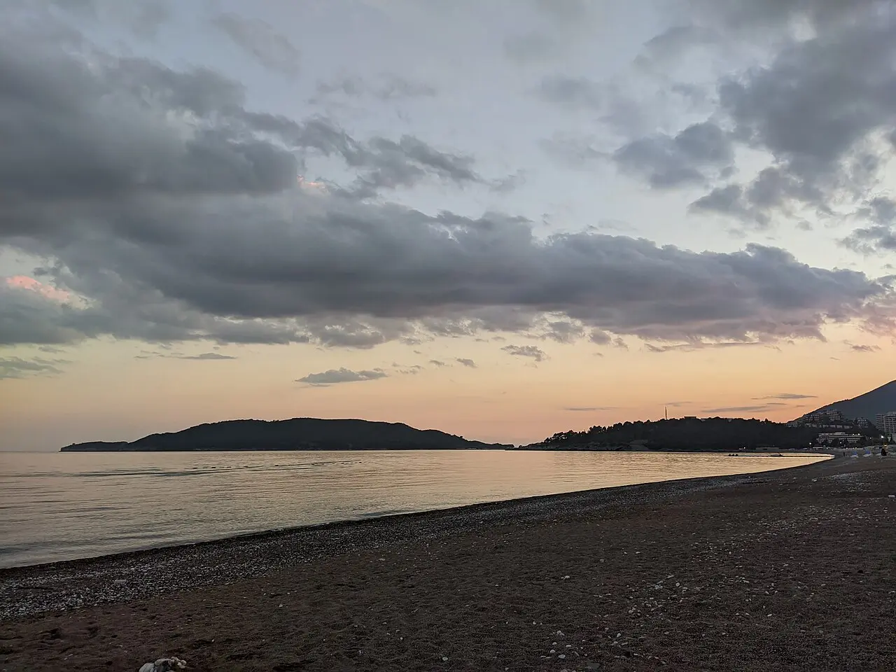 Bečići shoreline with mountains and sparse early-season beach furniture