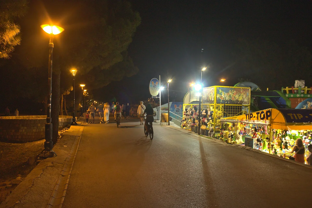 Budva seaside promenade at night, busy with people, lamps and stalls in summer
