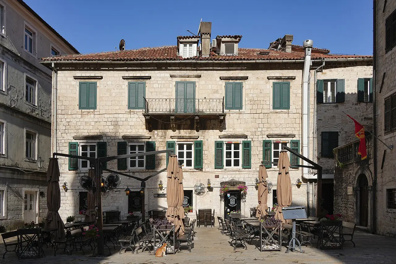 Empty café tables and folded parasols on the Square of Arms in Kotor early in the morning