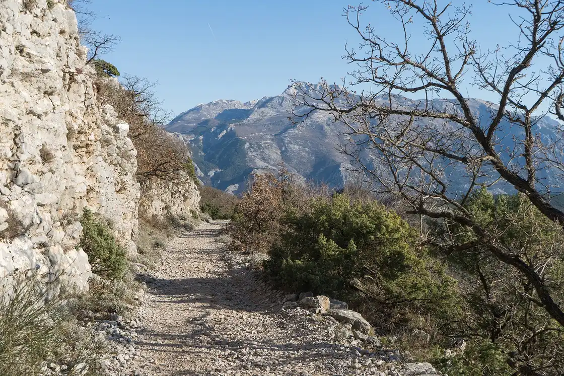 A stony hiking trail on Vrmac mountain above Kotor in February, with snow-dusted peaks in the distance