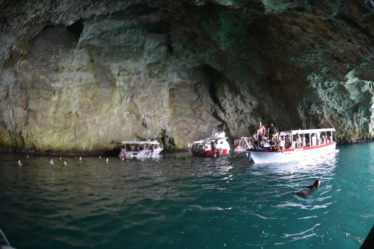 Swimmers in the bright blue water inside the Blue Cave, Lustica peninsula, Montenegro
