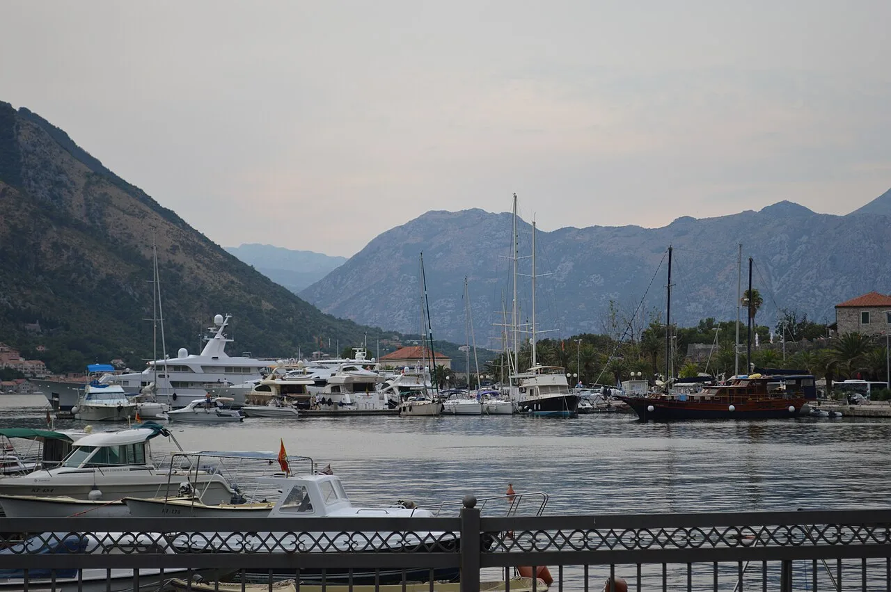 Small boats moored on the Bay of Kotor with steep mountains behind