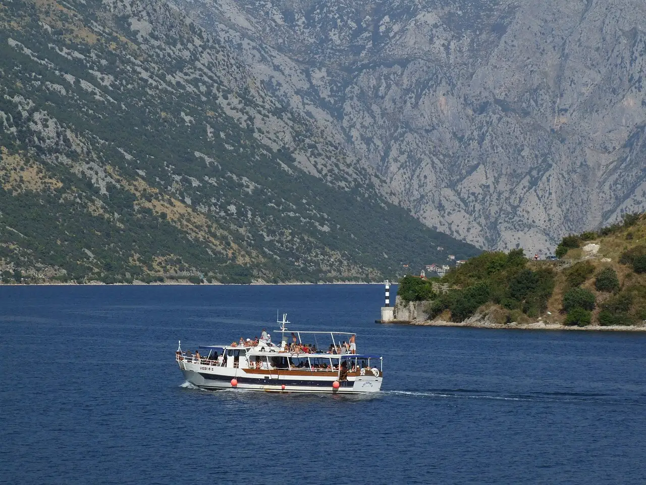 Motorboat moving across the Bay of Kotor with mountains behind