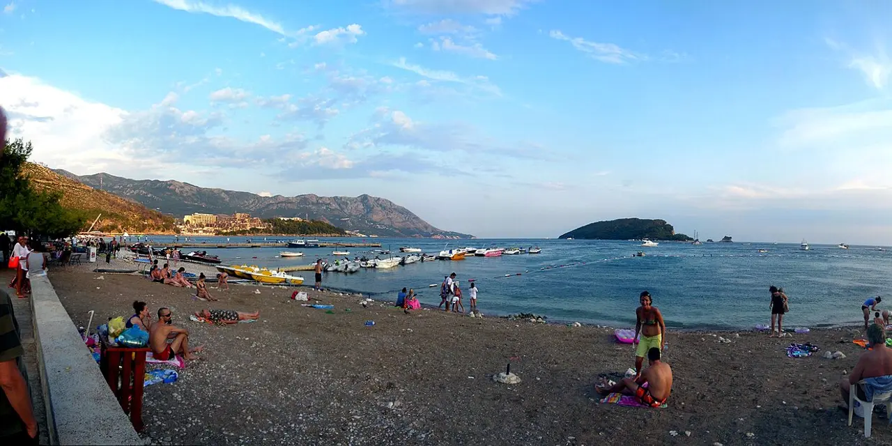 Budva town beach (Slovenska plaza) at dusk with the Sveti Nikola island offshore and mountains behind
