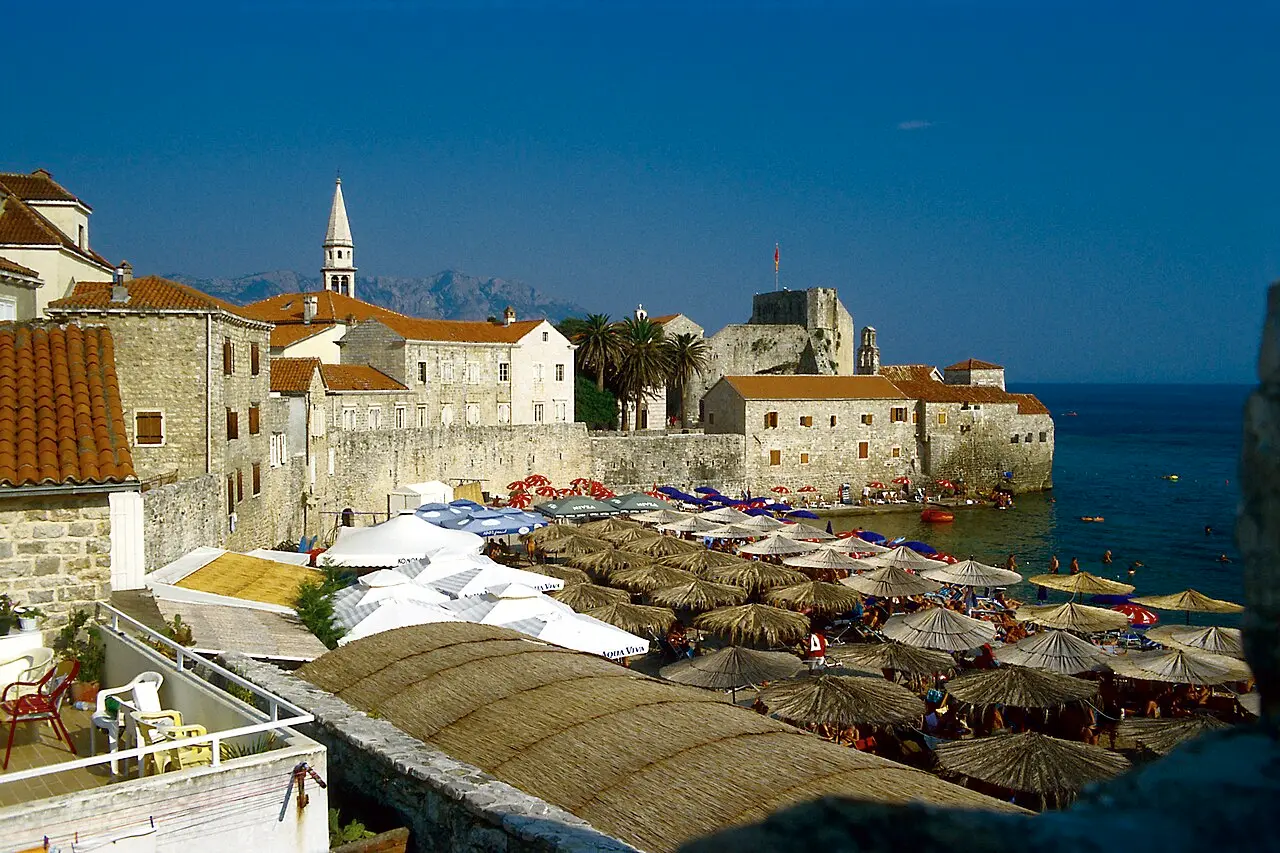 Budva city beach below the stone Citadel and Old Town walls at the tip of the peninsula