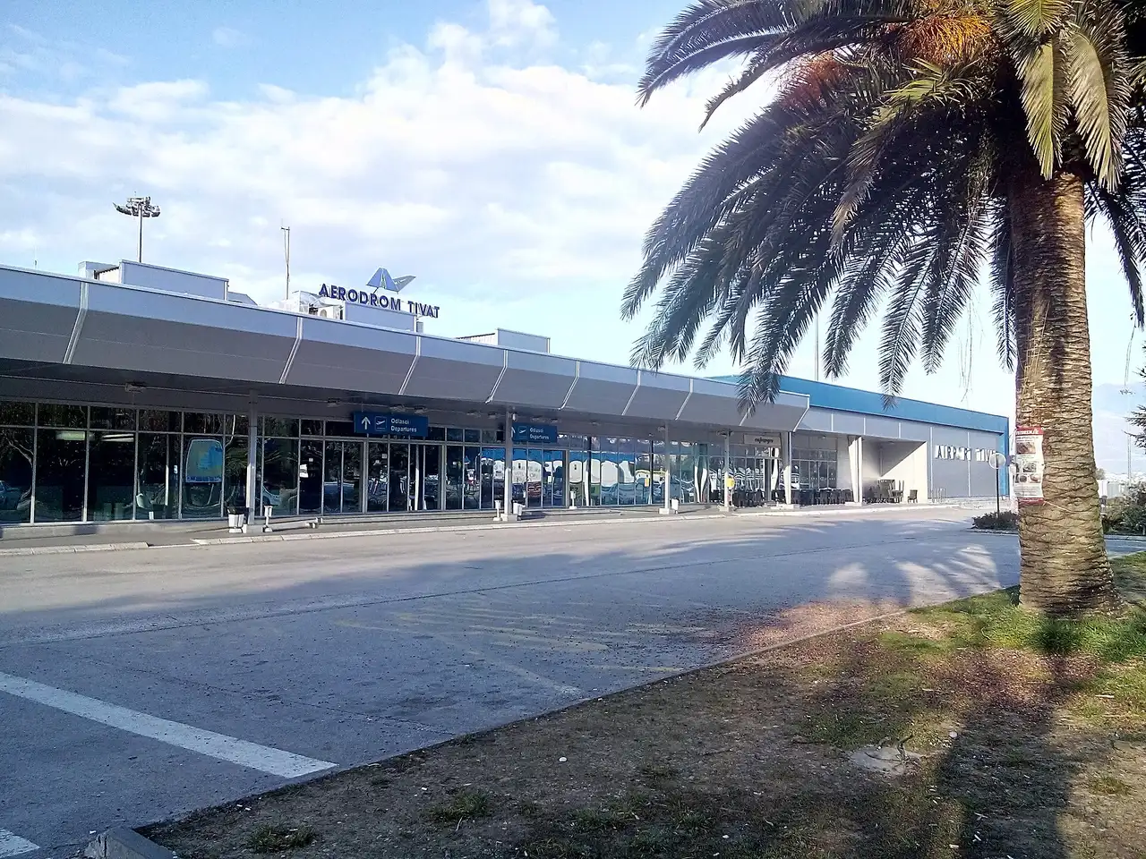 The low-rise passenger terminal of Tivat Airport (TIV) with the Aerodrom Tivat sign and a palm tree