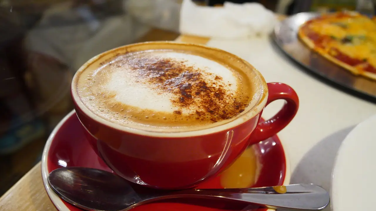A cappuccino dusted with cocoa in a red cup on a saucer