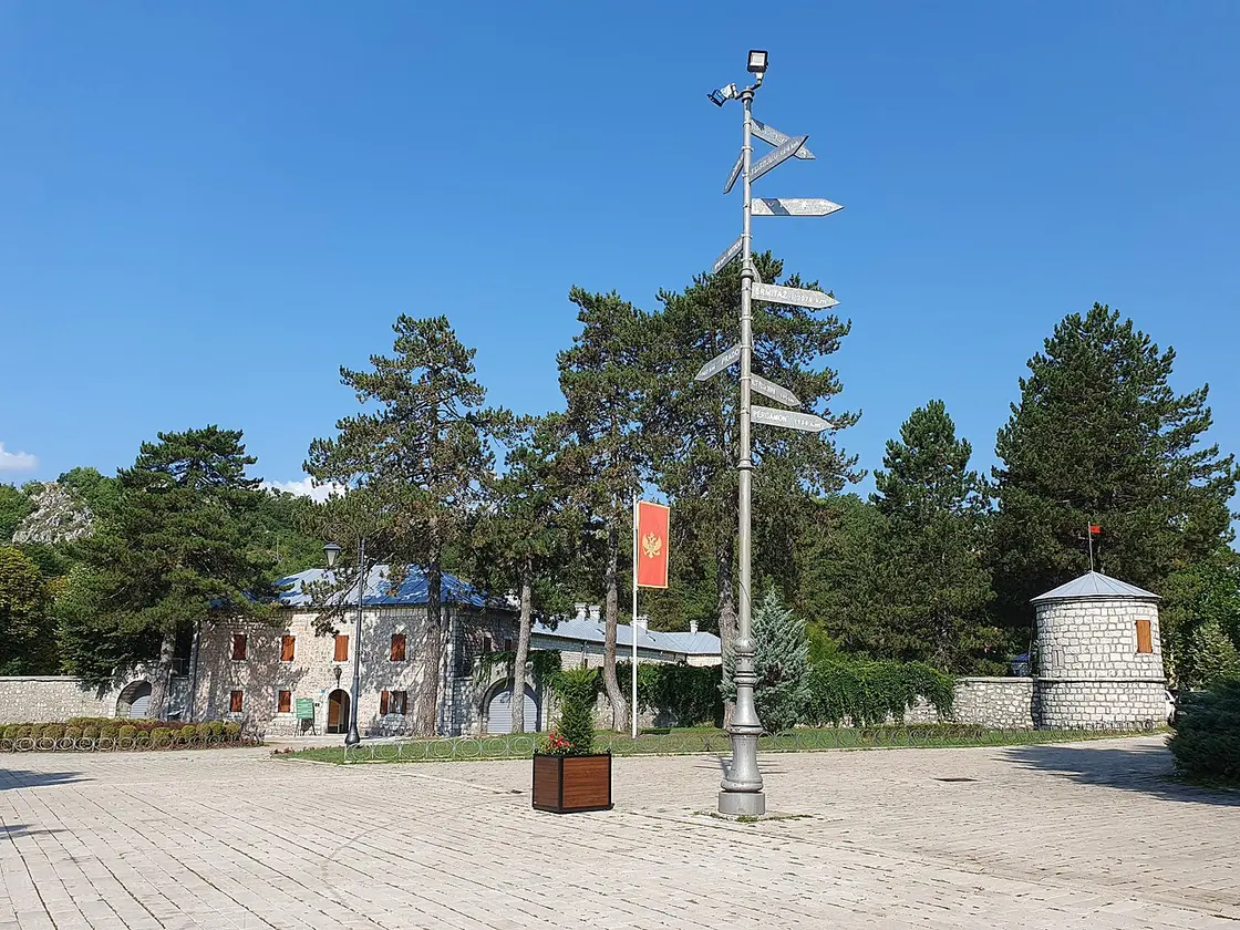 The long low stone Biljarda, Njegoš's former residence in Cetinje, across a square with a signpost