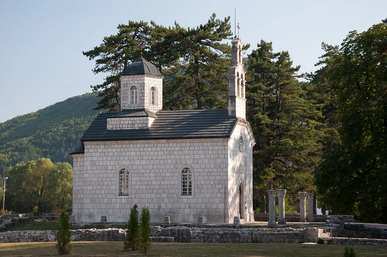 The white stone Court Church at Ćipur in Cetinje with a bell-cote and old column stumps in front