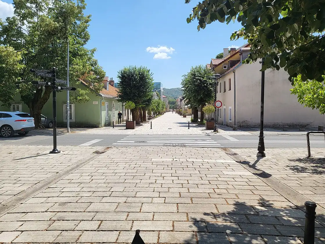 Njegoševa, the pedestrian main street of Cetinje, lined with trees and low old houses with a signpost to the monastery