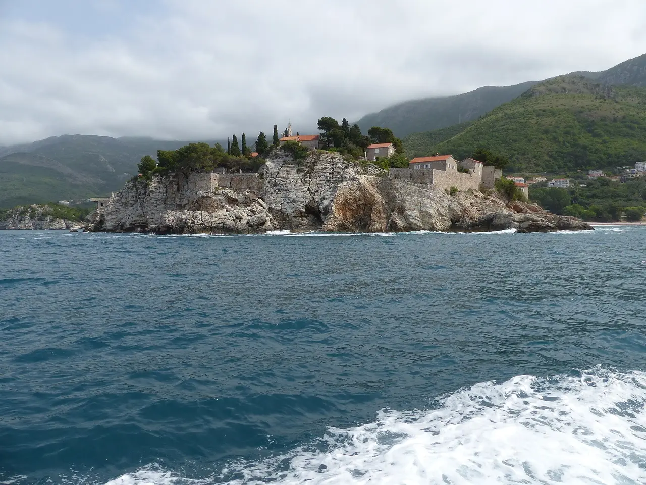 The islet of Sveti Stefan and its stone village seen from the water, Budva Riviera, Montenegro