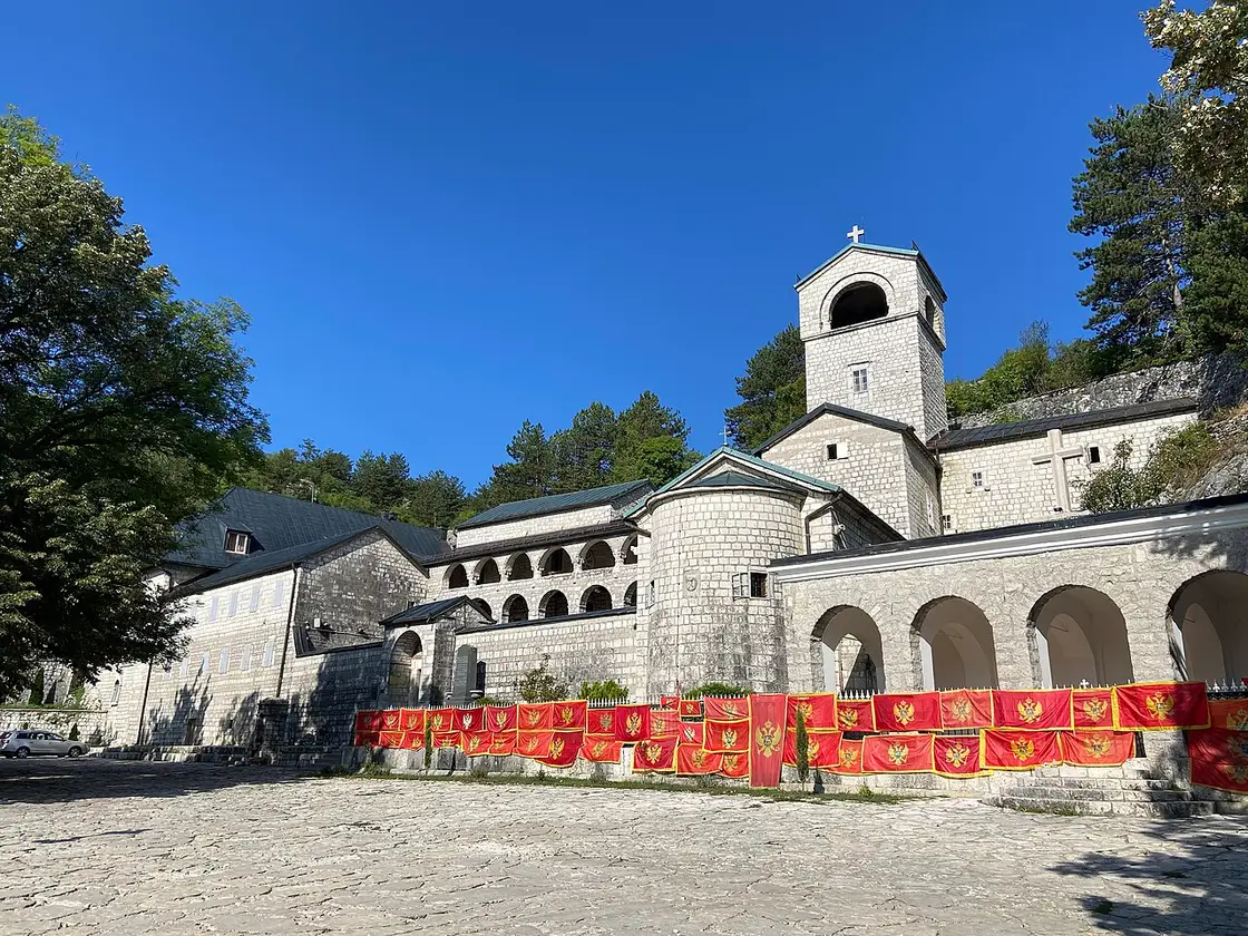 Cetinje Monastery with its bell tower and Montenegrin flags strung across the courtyard