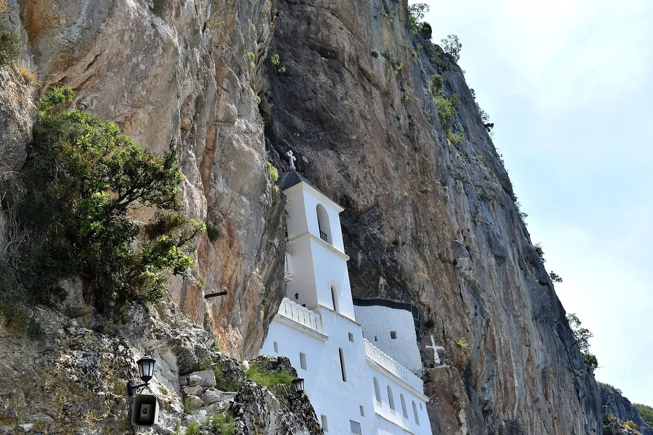 The white Upper Monastery of Ostrog set into the grey cliff above the wooded valley