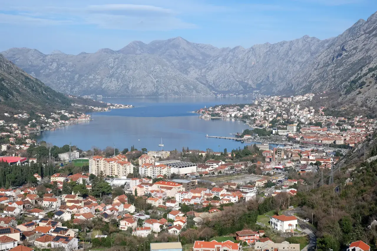 Bay of Kotor shoreline with mountains rising behind the coastal road toward Kotor