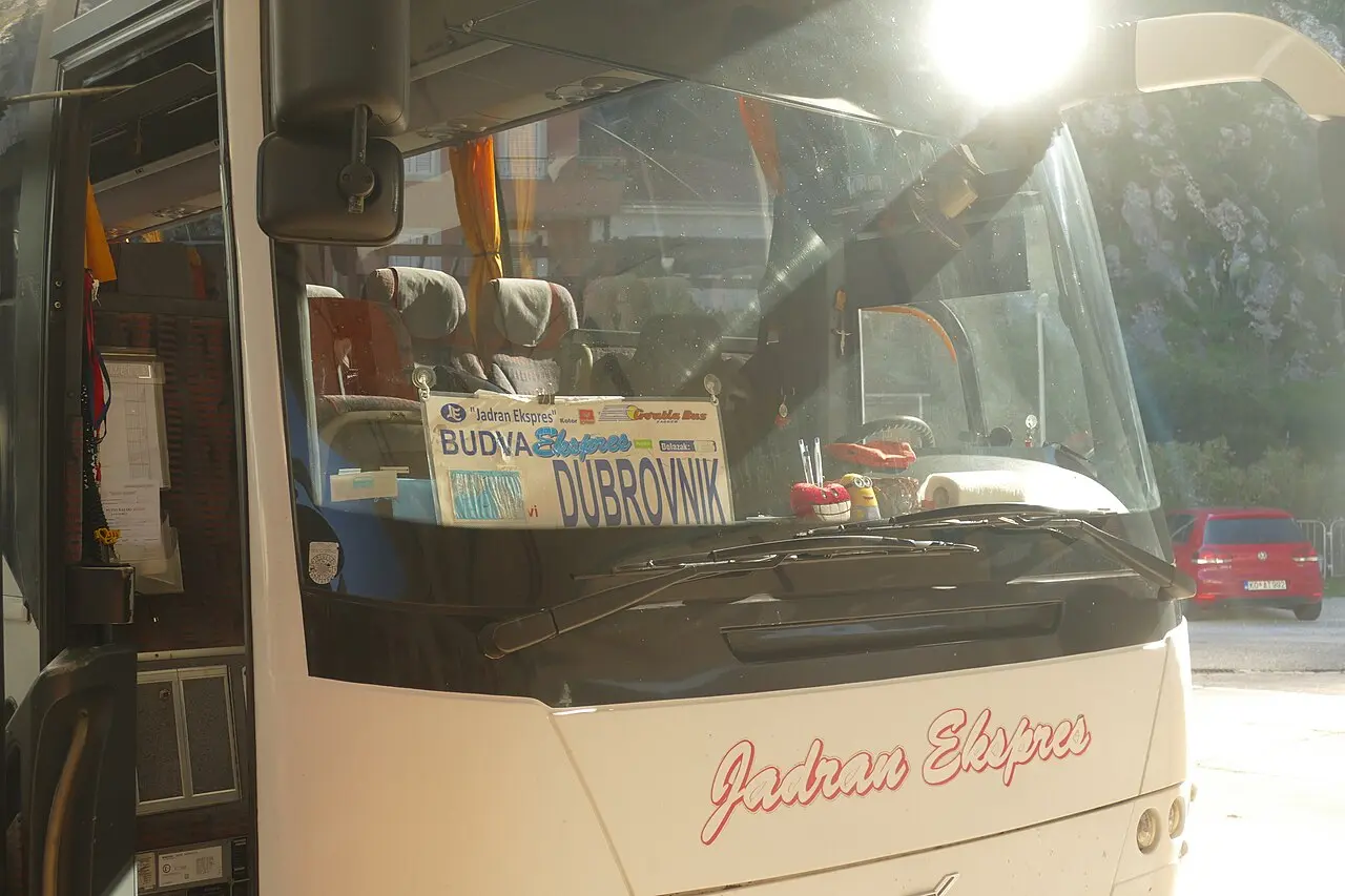 A Jadran Ekspres intercity coach at a Montenegrin bus station with a Budva-Dubrovnik destination sign
