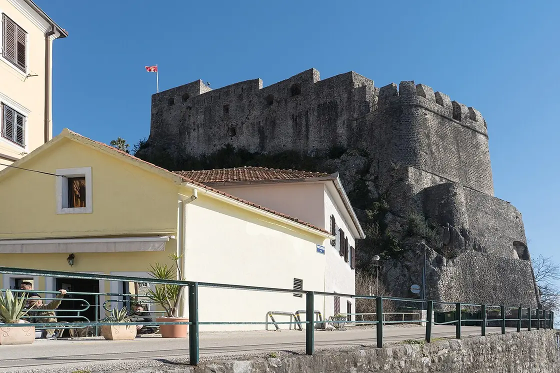 The stone walls and battlements of the Forte Mare sea fortress in Herceg Novi with the Montenegrin flag