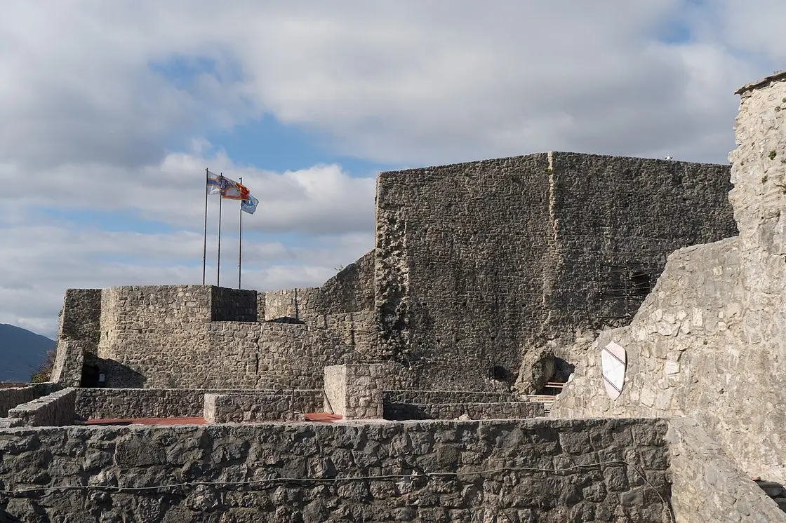 The massive grey stone ramparts of the Kanli Kula fortress in Herceg Novi under a blue sky