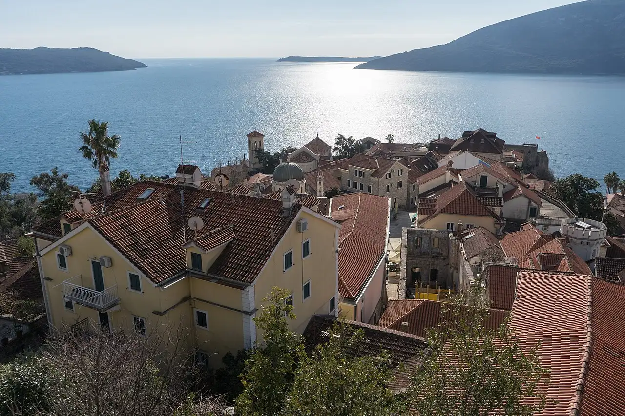Red-tiled roofs of Herceg Novi Old Town, the church dome and the bay glittering in the sun beyond