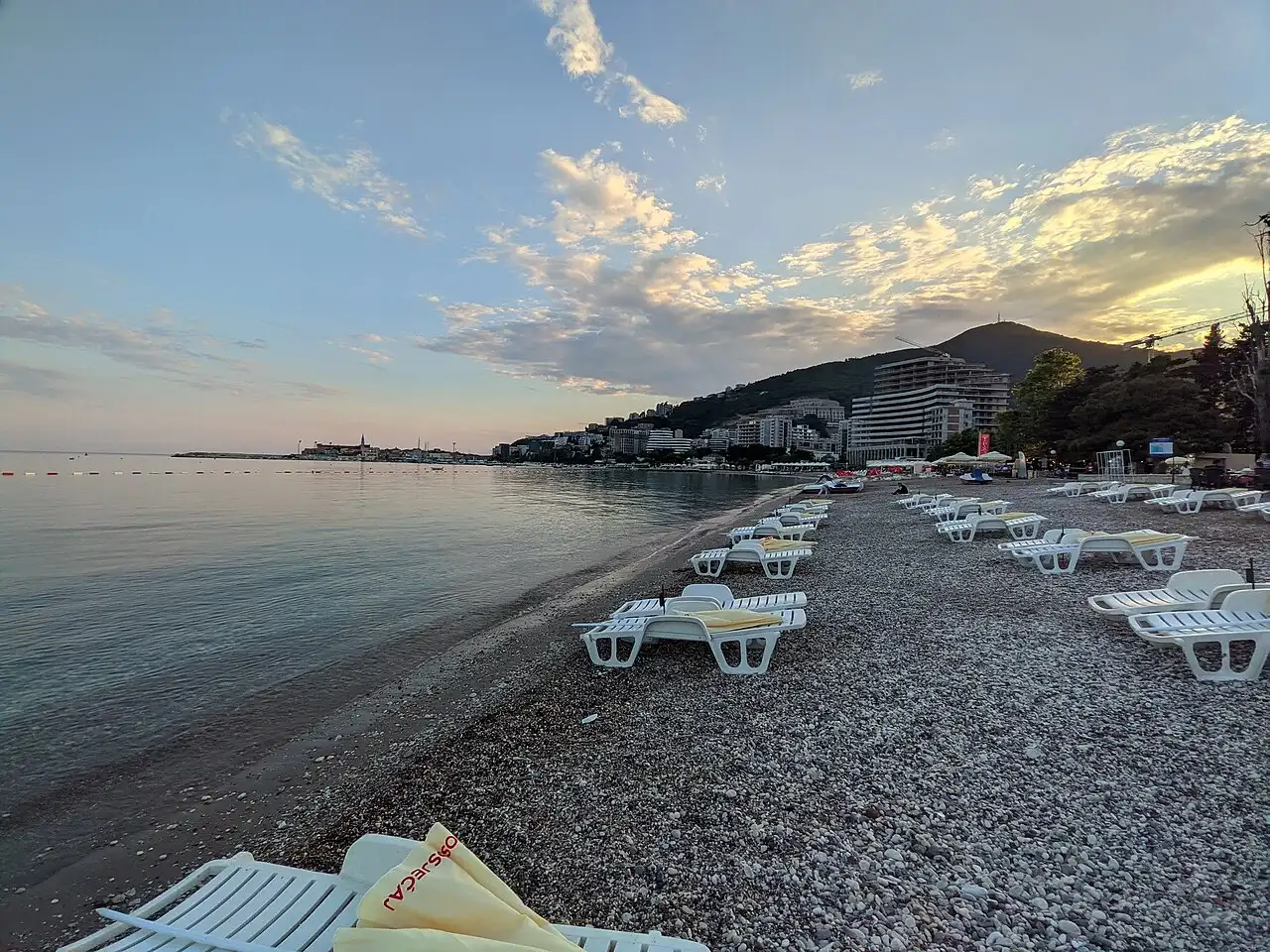 Budva beach at sunset with sun loungers and the town behind, Montenegro