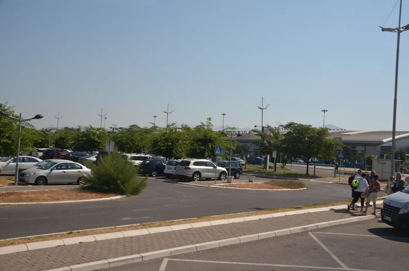 The car park at Podgorica Airport, with passengers walking toward the terminal building