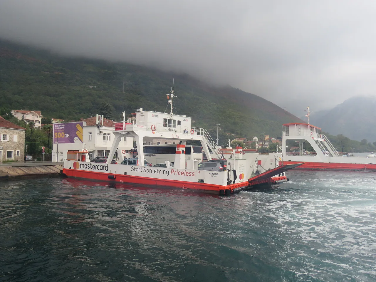 Cars loaded on the deck of the Kamenari ferry with the bow ramp lowered at the terminal on the Bay of Kotor