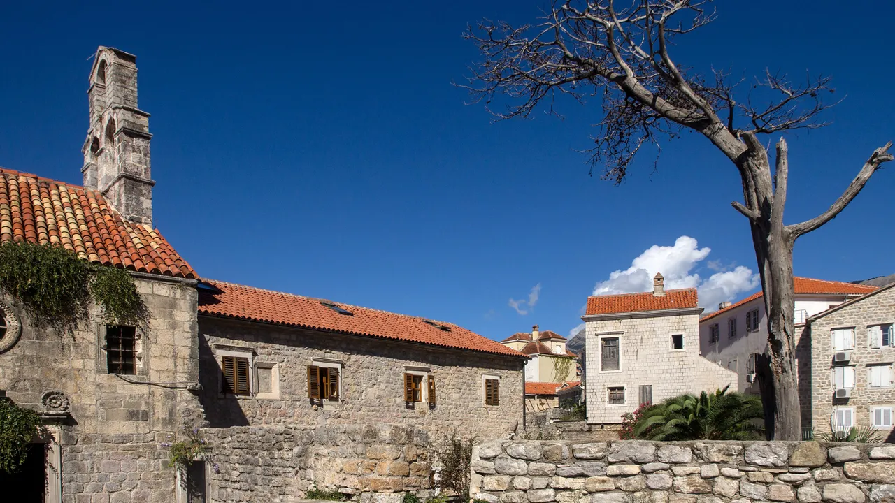 Stone facades and a church bell tower in Budva Old Town