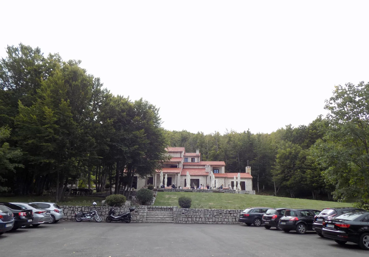 A stone mountain lodge with a terrace among beech woods at Ivanova Korita on Lovcen, with cars parked in front
