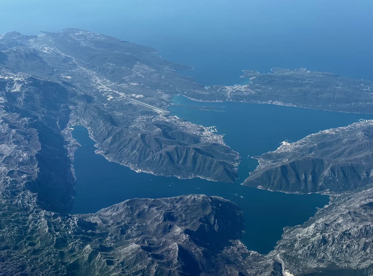 Aerial view of Kotor old town at the head of the bay with the fortress walls climbing the hillside above it