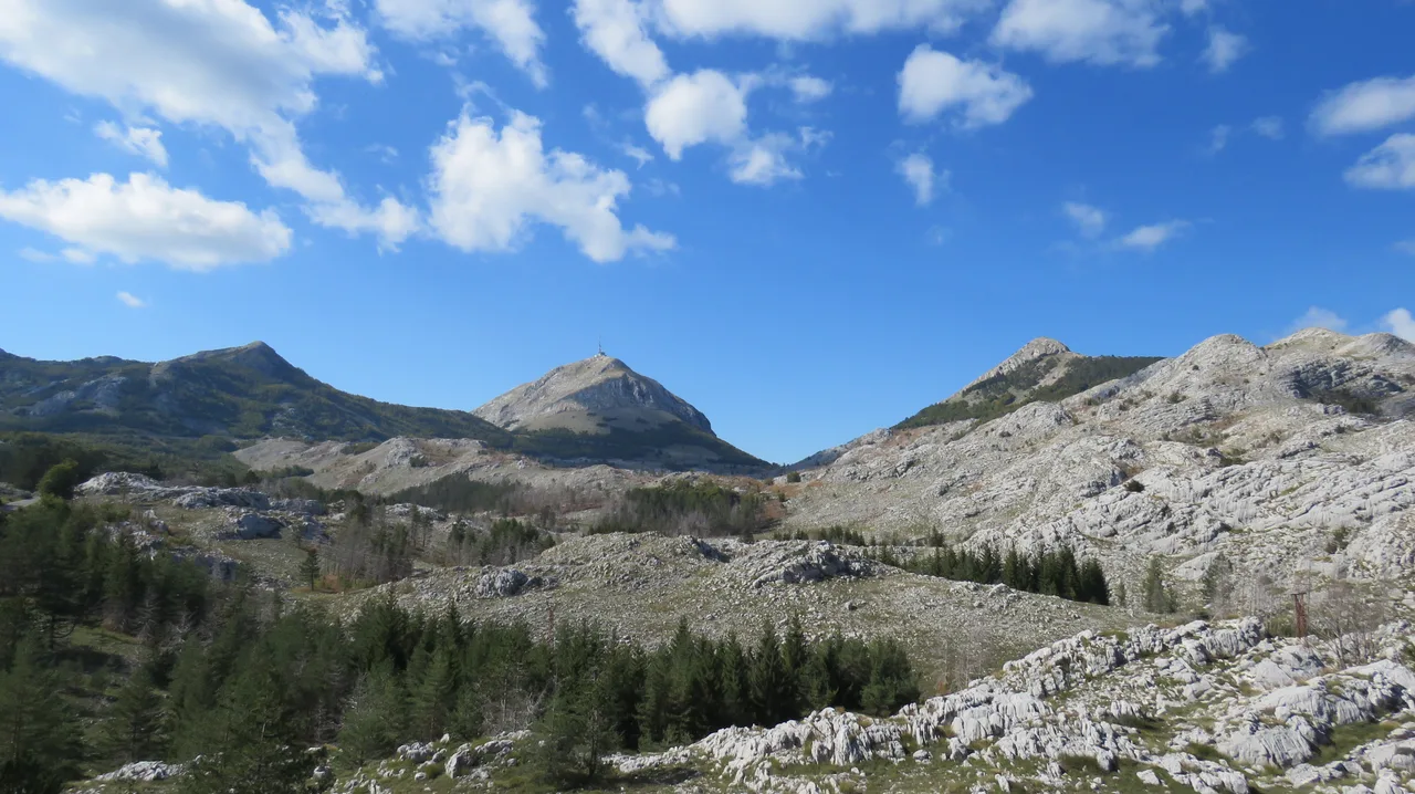 The karst plateau and peaks of Lovcen under a blue sky, with the antenna on the summit of Stirovnik visible