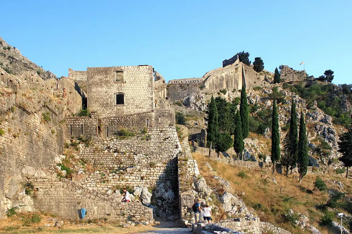Worn stone steps of the walled path climbing above Kotor with the bay behind