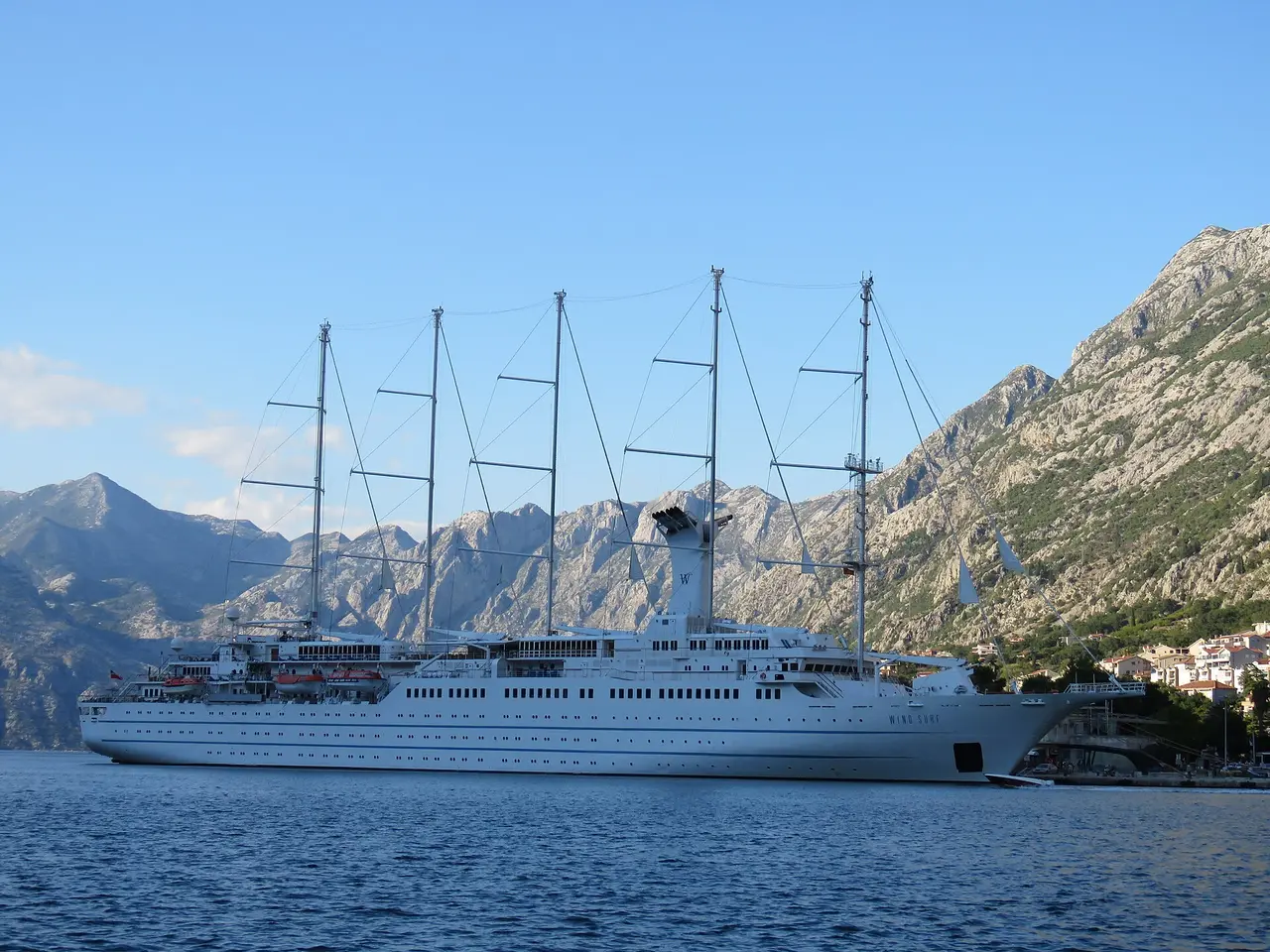 A sailing cruise ship anchored in the Bay of Kotor below steep grey mountains, Montenegro