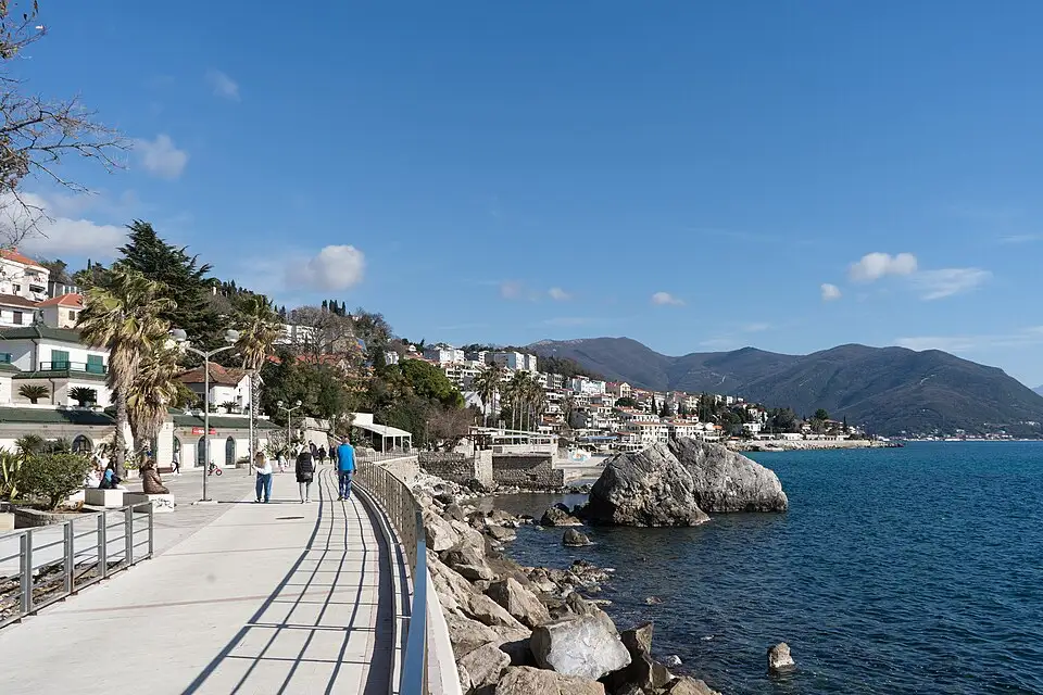 Stone archway on the Pet Danica seaside promenade in Herceg Novi framing the blue bay