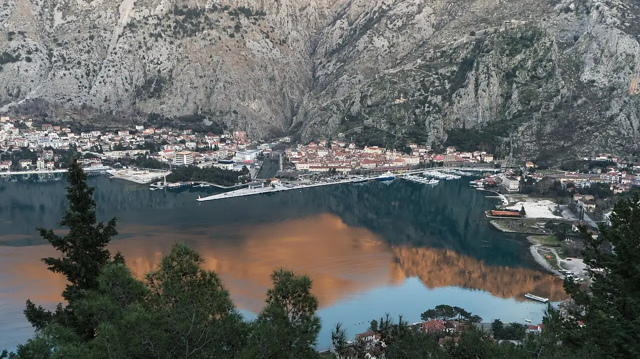 Kotor old town at the head of the Bay of Kotor, ringed by grey mountains, seen from the Vrmac trail above