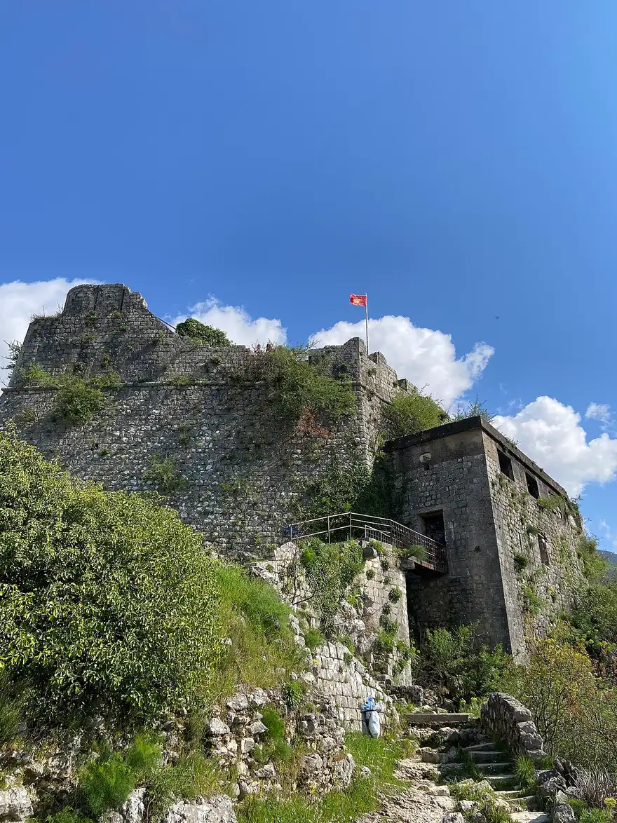 The ruined San Giovanni fortress on the ridge above Kotor with the Montenegrin flag