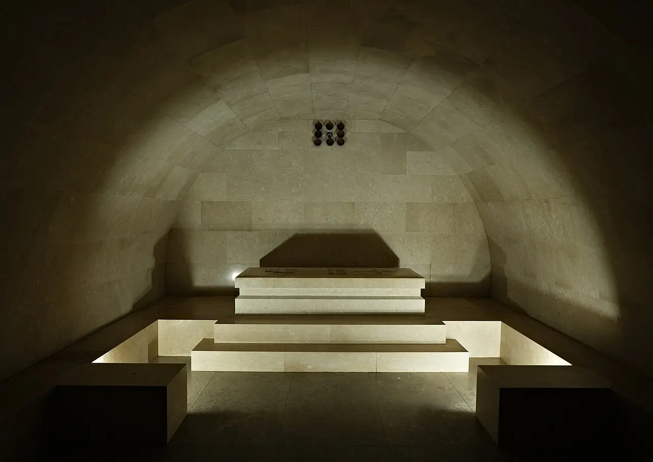 The vaulted stone crypt of the Njegoš Mausoleum with the black granite sarcophagus lit on a stepped platform