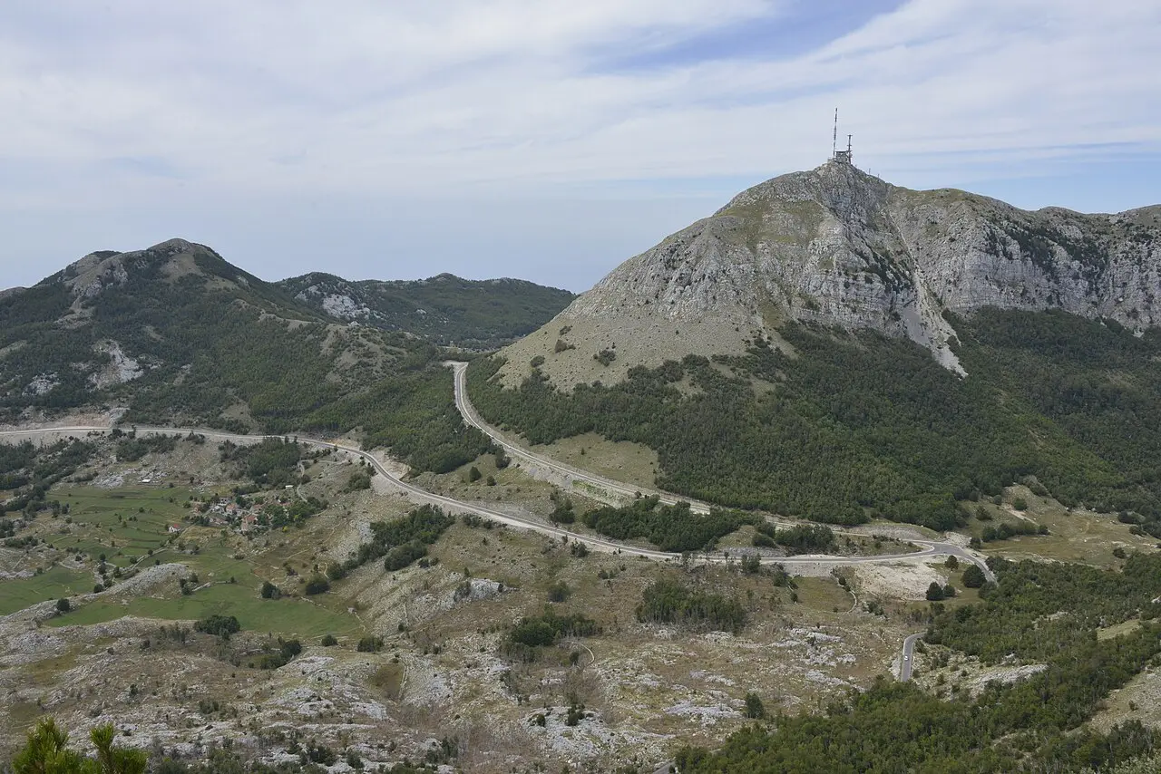 The Lovćen massif with the antenna-topped Štirovnik peak and the mountain road winding below, Montenegro