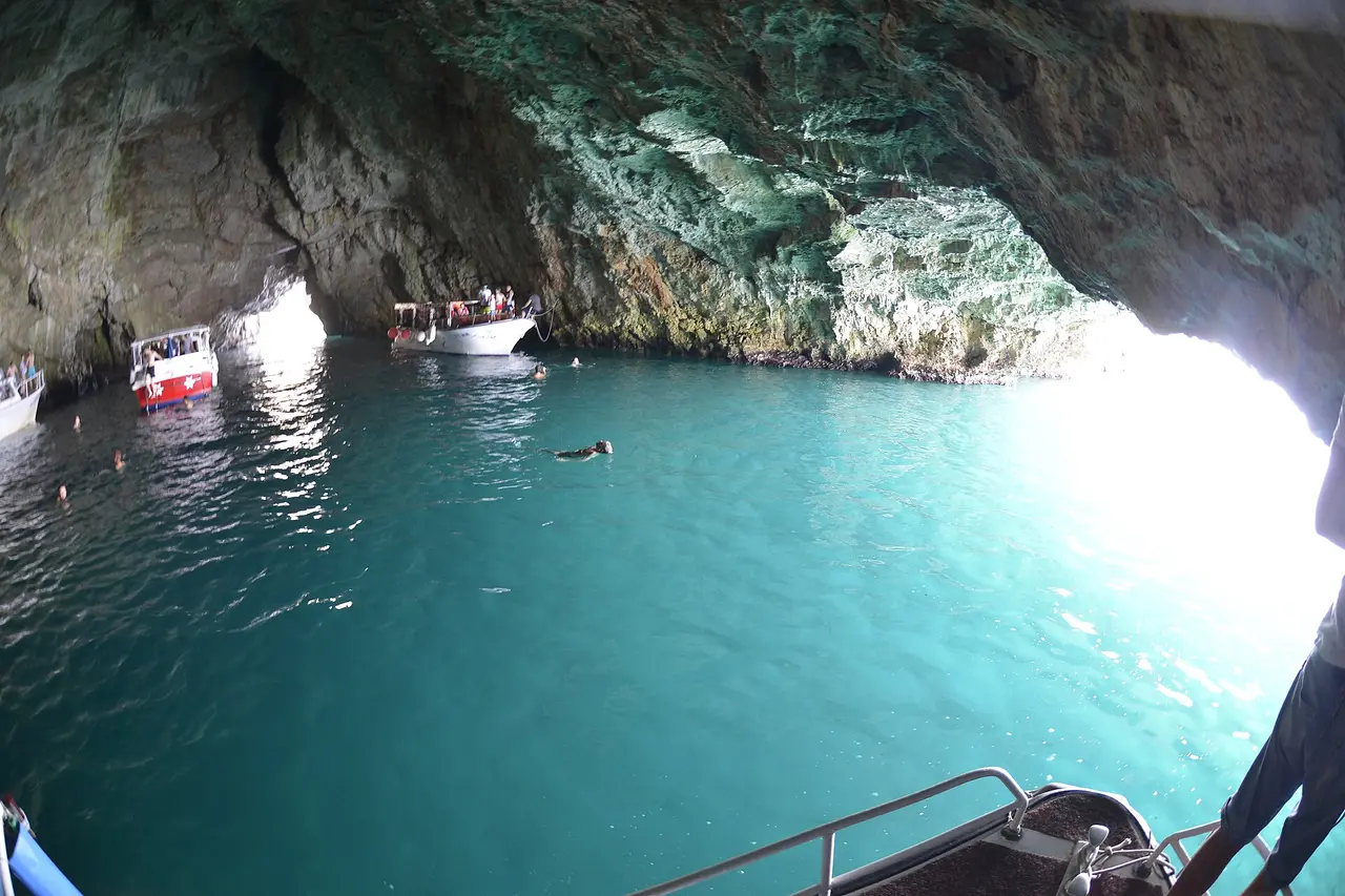 The interior of the Blue Cave near Lustica, its water glowing bright turquoise, with small tour boats and swimmers