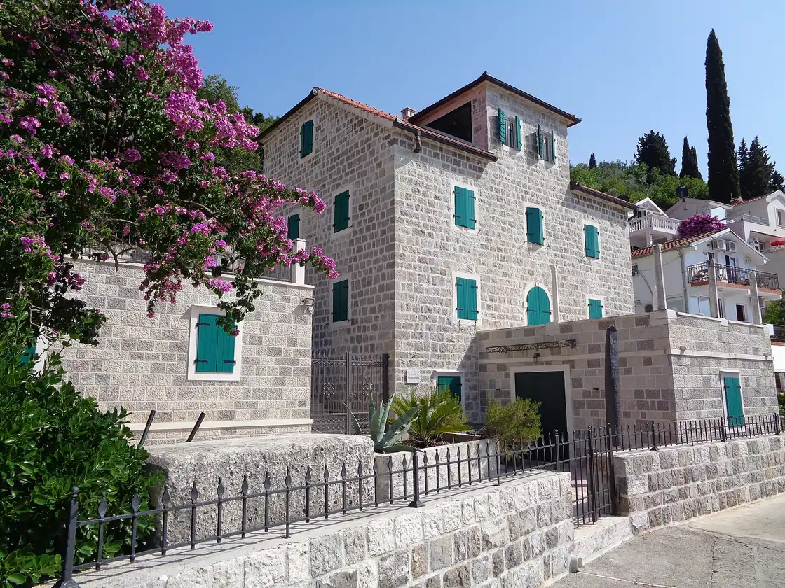 A restored stone house in Rose village with green shutters and bright pink bougainvillea